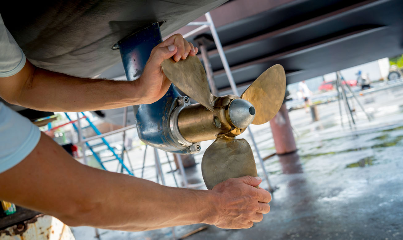Person inspecting a boat propeller during routine boat maintenance