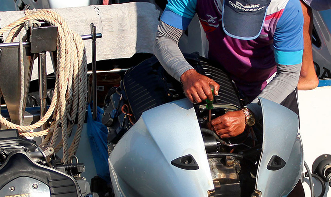 Technician performing outboard engine diagnostics on a boat