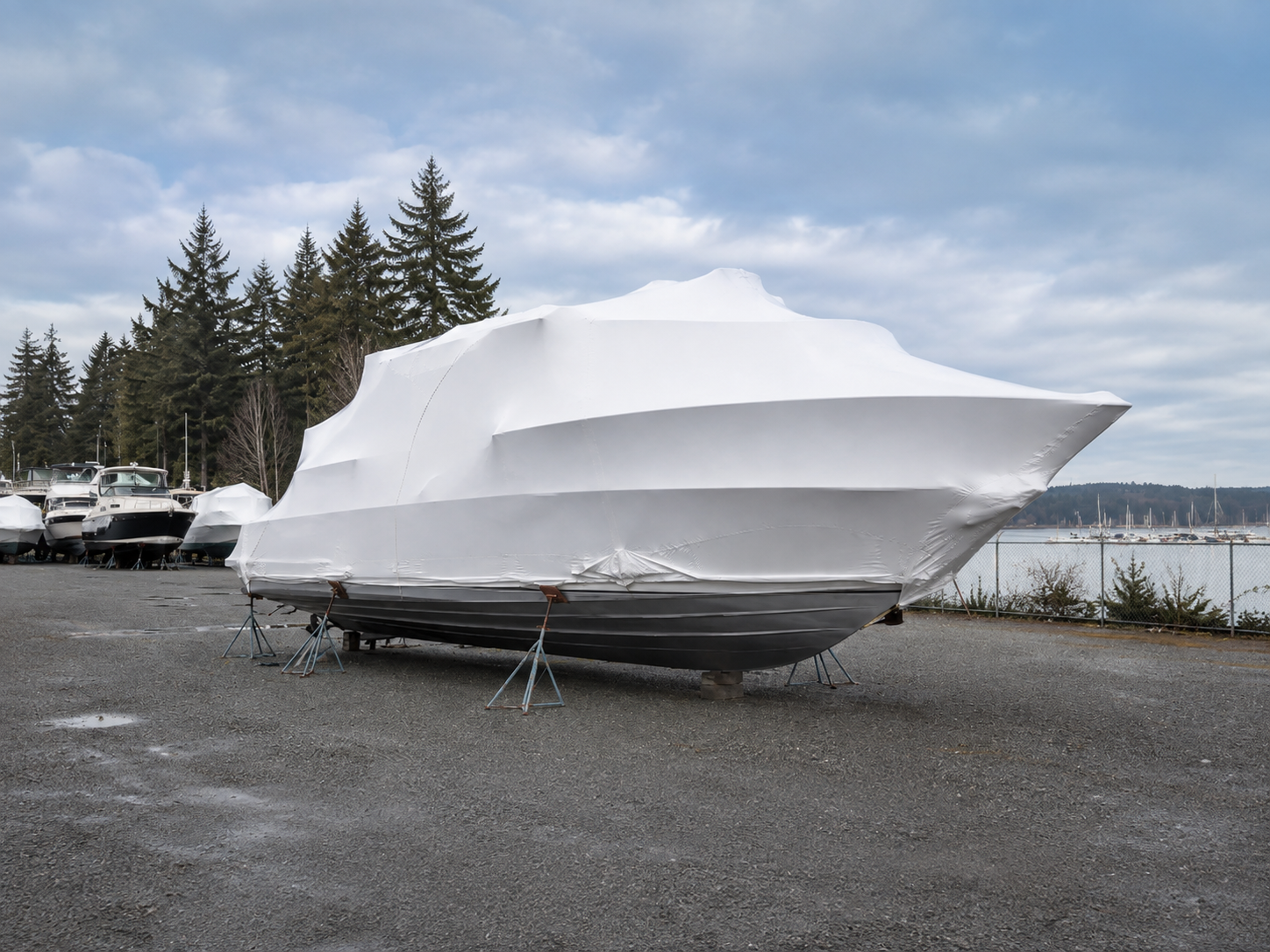 Boat professionally wrapped in white shrink wrap for winter storage at a marina in Western Washington.